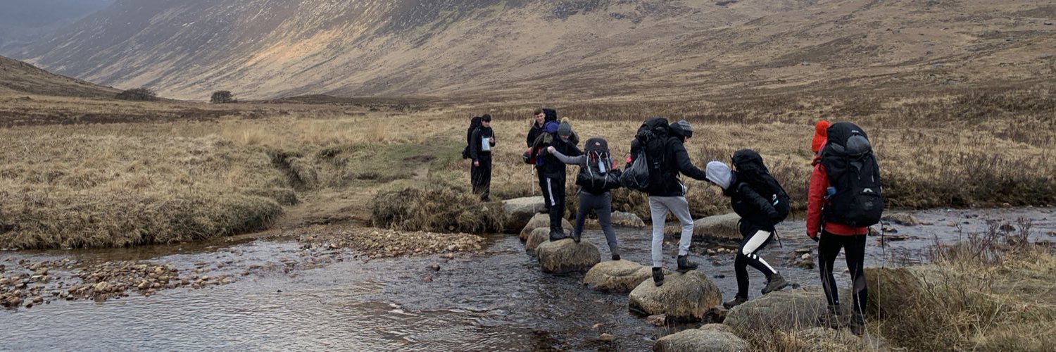 Young people hiking over a river