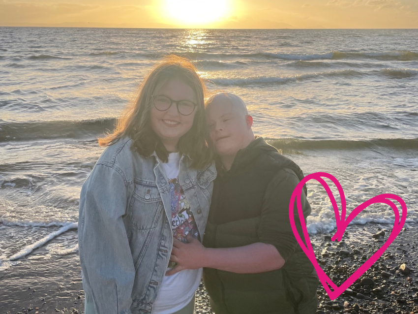 Sarah and her brother Patrick in front of the sun setting at sea